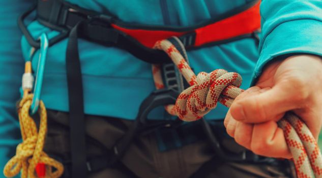 Rock climber wearing safety harness, rope and climbing equipment, close-up image