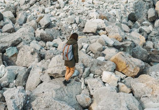 Traveler young woman with backpack walking on stones