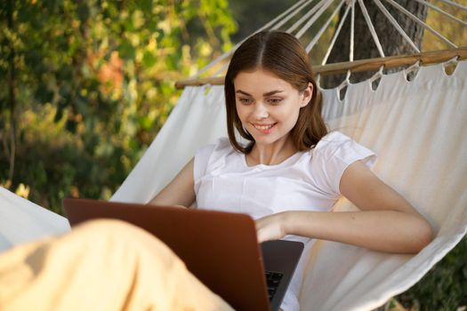 women outdoors lies in a hammock with a laptop freelance internet. High quality photo