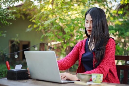 young woman using laptop and drinking coffee in the garden