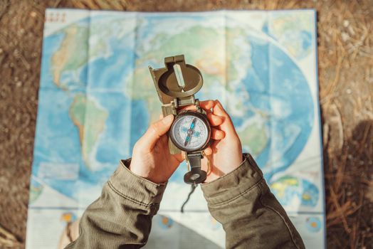 Traveler woman searching direction with a compass on background of map outdoor. Close-up. Point of view shot