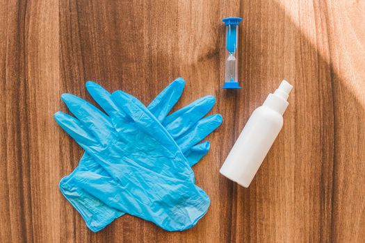 Protective medical gloves and a antiseptic on the table with an hourglass.