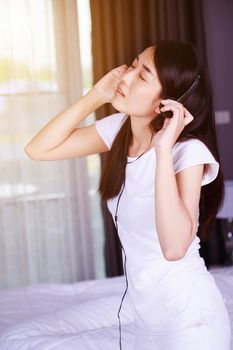 woman in headphones listening to music from smartphone in the bedroom