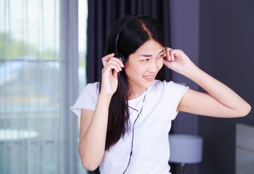 woman in headphones listening to music from smartphone with the window background