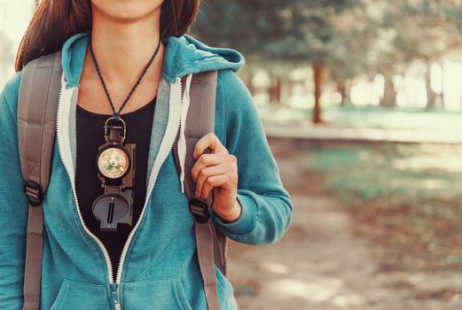 Tourist girl with backpack and compass walking in summer forest