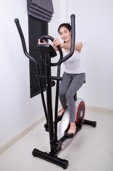 young sporty woman doing exercises with elliptical trainer