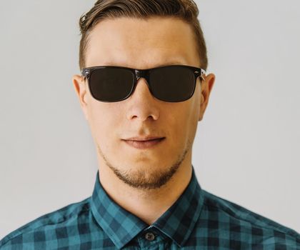 Portrait of handsome young brunet man in sunglasses and plaid shirt