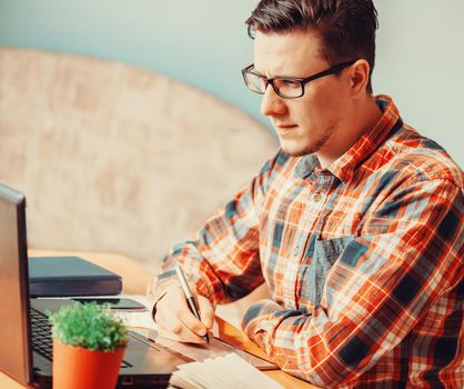 Young man working with graphics tablet over laptop in the office