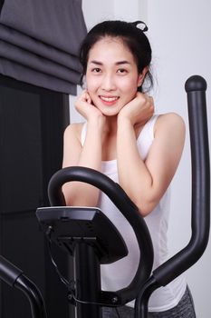 young sporty woman doing exercises with elliptical trainer