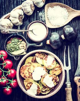 fried zucchini with sour cream and spices on wooden table, top view