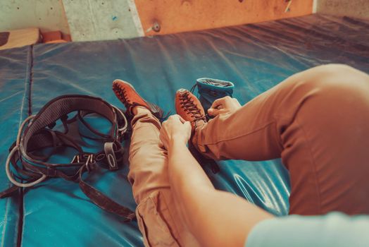 Woman putting on climbing shoes and preparing to climb, view of legs