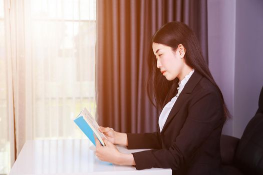 young business woman sitting at the desk and reading a book