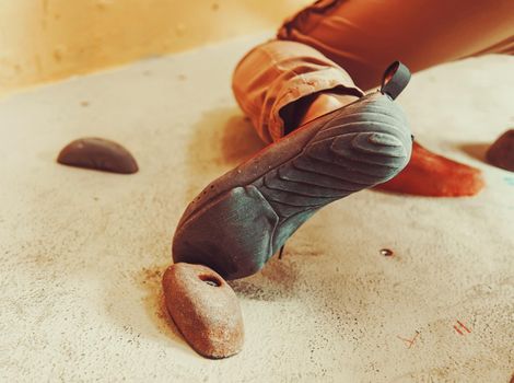 Close-up image of climber female foot on artificial boulder indoors