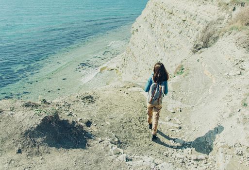 Young woman walking down to the sea in summer