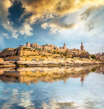 view on Valletta with its architecture from the sea at sunset with reflection