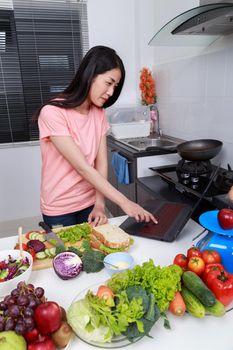 young woman cooking and looking with laptop in kitchen room