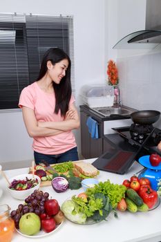 young woman cooking and looking with laptop in kitchen room