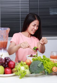 unhappy young woman eating salad in kitchen