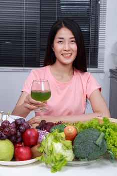 young woman drinking vegetable juice in kitchen
