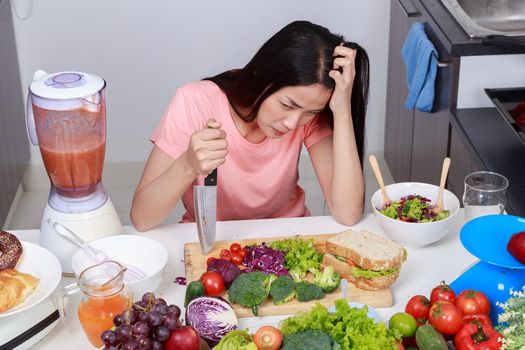 depressed young woman cooking with knife in kitchen room