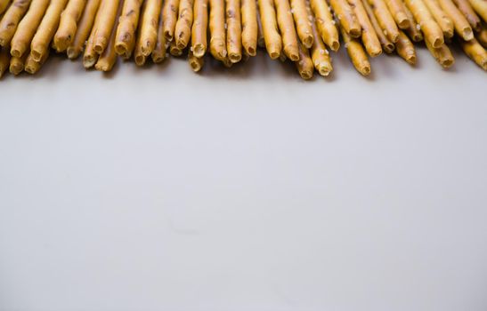 Background from sticks of crackers with salt on a gray background. Food concept. Edible snacks dry sticks with salt. Texture from straws, crackers sticks