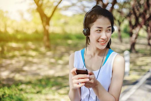 young sporty woman using smartphone with headphone in the park