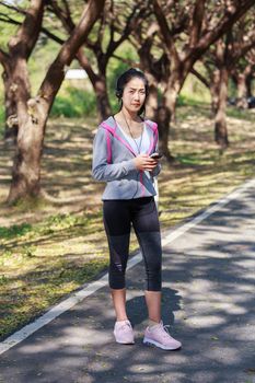 young sporty woman using smartphone with headphone in the park