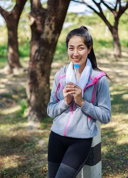 young sporty woman with bottle of water in the park