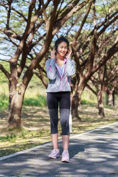 young sporty woman listening music with headphone in the park