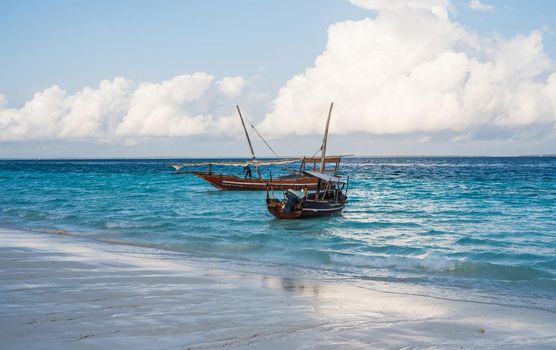 two african boats near the shore with beautiful colorful sea and sky on the background