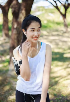 Young woman listening to music with earphones on smart phone app in the park