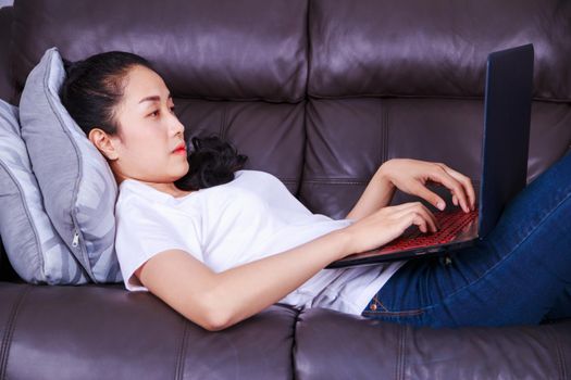 young beautiful woman using a laptop computer on sofa in living room at home