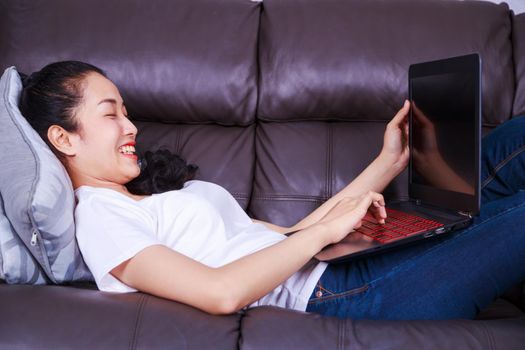 young beautiful woman using a laptop computer on sofa in living room at home