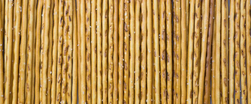 Background from sticks of crackers with salt. Food concept. Edible snacks dry sticks with salt. Texture from straws, crackers sticks
