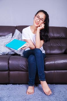 young woman with a book on sofa at home