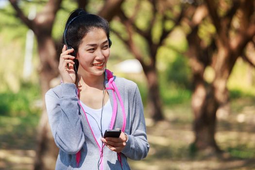 young sporty woman using smartphone with headphone in the park