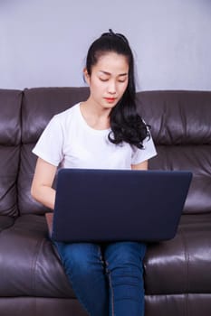 young beautiful woman using a laptop computer on sofa in living room at home