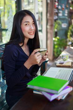 young woman using laptop at cafe while drinking coffee