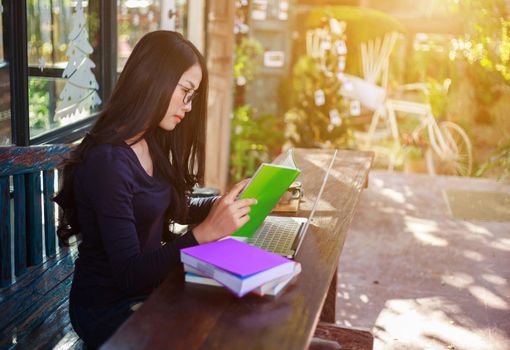 young woman working and reading a book in the laptop