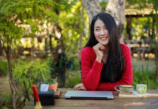 portrait of young woman with laptop and coffee in the garden