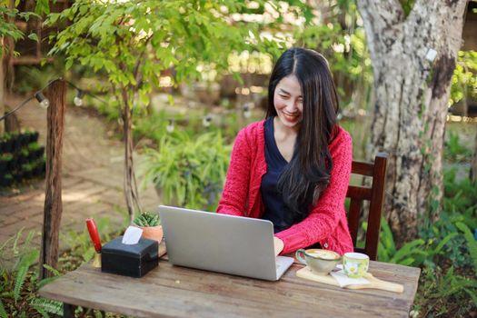 young woman using laptop and drinking coffee in the garden