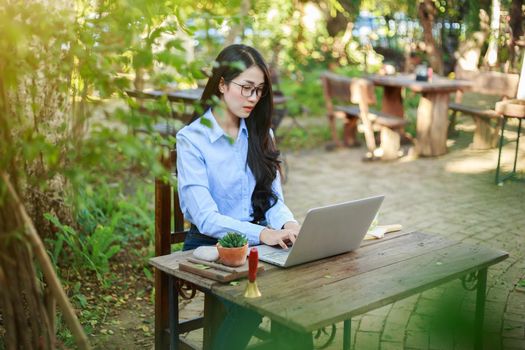 young woman using laptop and drinking coffee in the garden