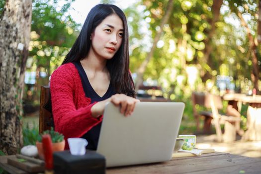 young woman using laptop and drinking coffee in the garden