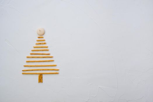 Christmas tree made from pepero straws cookies, on white background texture. Top view with space for text on the right.