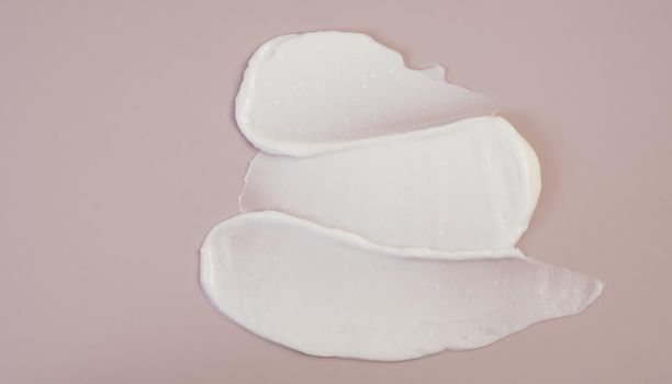 White beauty cream lotion highlighter smear swatch smudge on pink background.