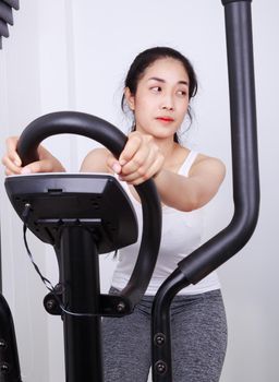 young sporty woman doing exercises with elliptical trainer