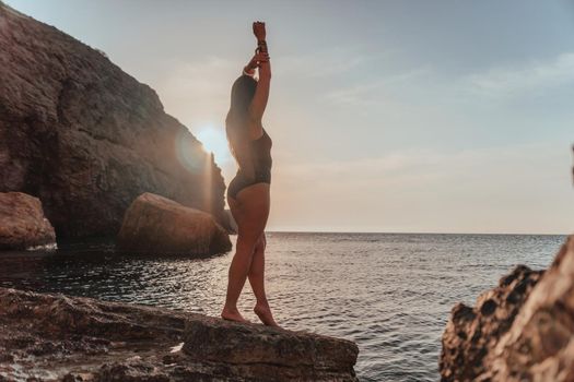 Young woman in swimsuit with long hair practicing stretching outdoors on yoga mat by the sea on a sunny day. Women's yoga fitness pilates routine. Healthy lifestyle, harmony and meditation concept.