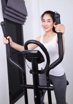 young sporty woman doing exercises with elliptical trainer