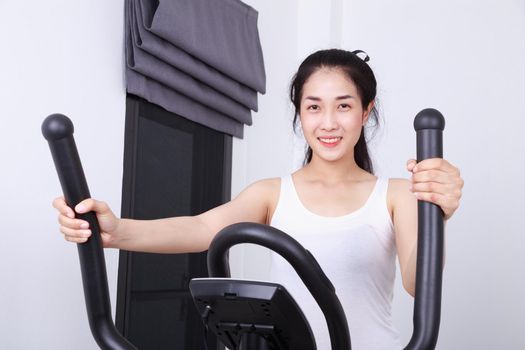 young sporty woman doing exercises with elliptical trainer