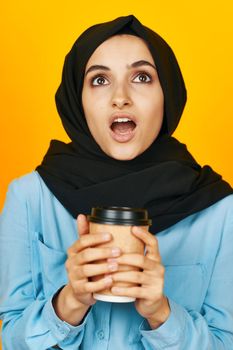 woman in black hijab a glass of coffee in hands near the face studio lifestyle. High quality photo
